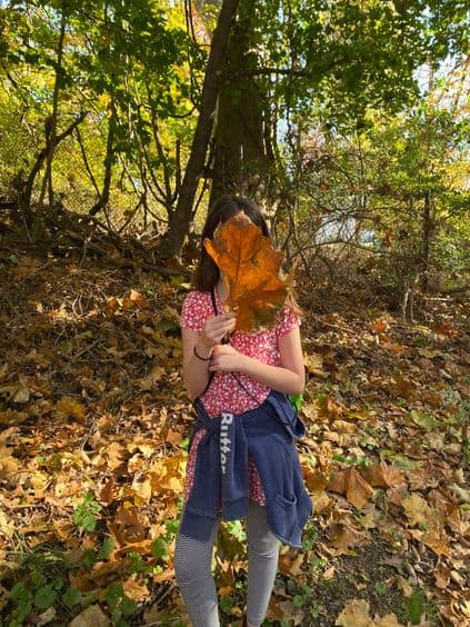 Young girl at Sheldrake holding large leaf in front of her face.