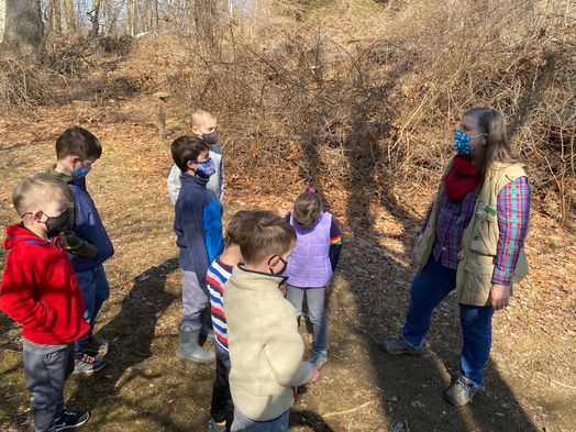 group of kids at Sheldrake in woods with a naturalist teaching them.