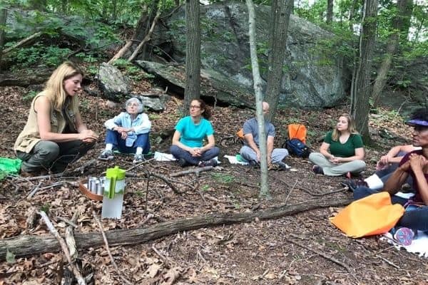 Adults sitting in circle in the woods practicing mindfulness at Sheldrake.