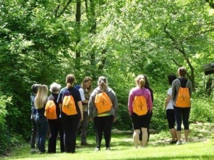 Group of adults hiking in the green Sheldrake trees.