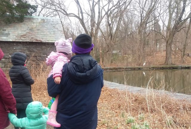 Young family looking out at Sheldrake pond dressed in winter gear.